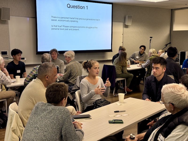 OLLI members and Berkeley students deep in conversation gathered around tables