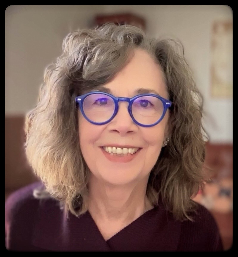 Kathleen Moran wearing bright blue spectacles smiling at camera