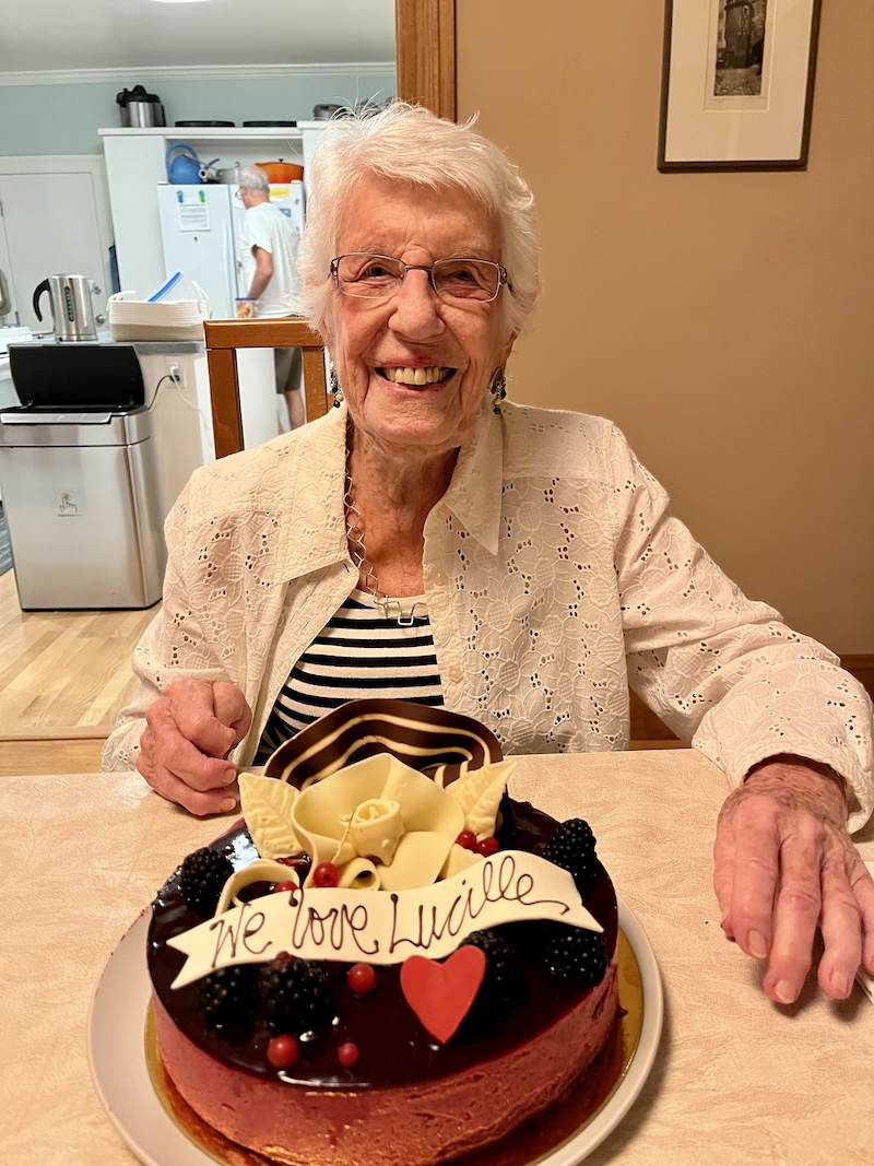 A smiling Lucille Poskanzer  with a birthday cake with "We Love You" written on it