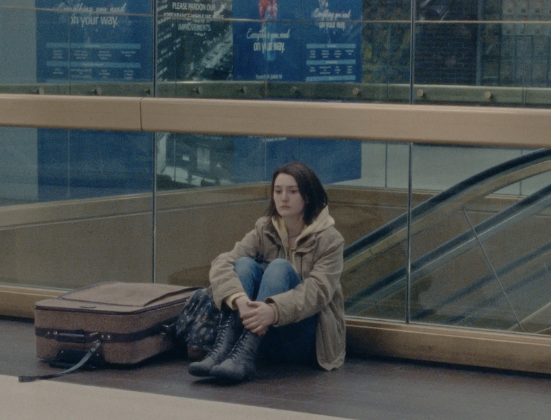 A forlorn teenage girl sitting on ground in a transit station, a scene from Never, Rarely, Truly