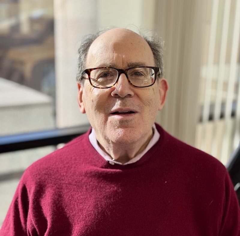 Closeup of a red-sweater clad Steve Harris against window
