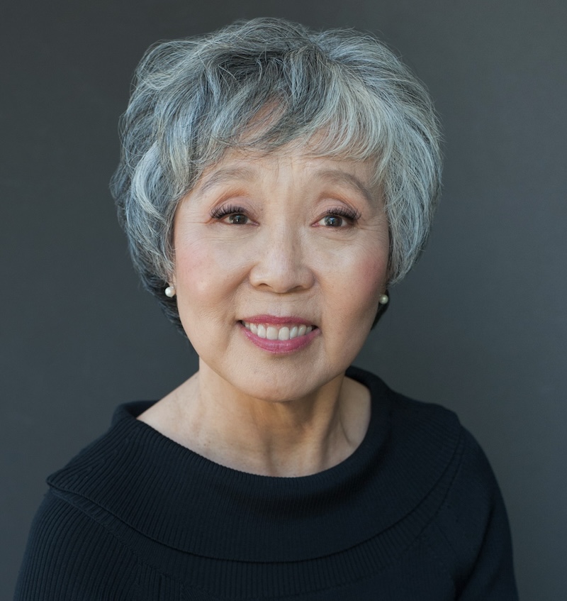 A gray-haired woman smiling at camera